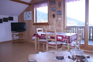 Ein Zimmer mit einem hölzernen Etagenbett, einem Fernseher und einem Tisch mit roter Tischdecke.