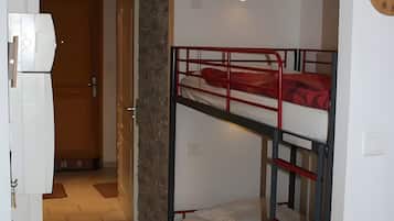 Une pièce avec des lits superposés, une horloge murale et une porte donnant sur une autre pièce.