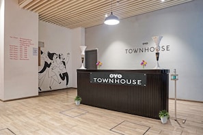 Una recepción con un letrero que dice 'OYO TOWNHOUSE' y una lista de nombres y números de pisos en la pared.