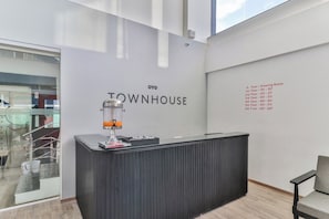 A reception desk with a modern design, a glass partition, and a list of room numbers on the wall. - Townhouse Reva College University (Bangalore)