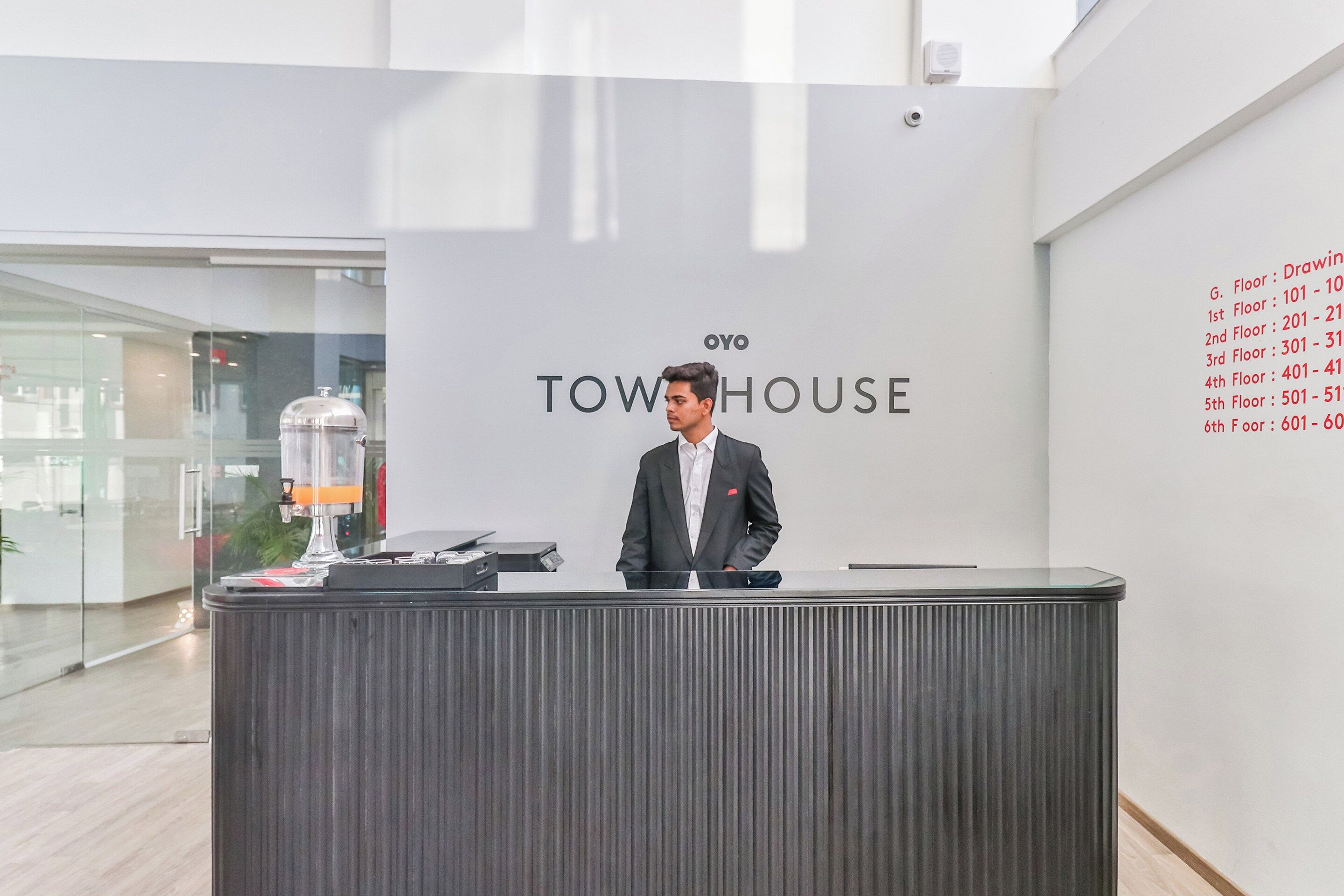Un comptoir d’accueil avec une enseigne indiquant « TOWHOUSE » et une liste des numéros d’étage affichée sur le mur.