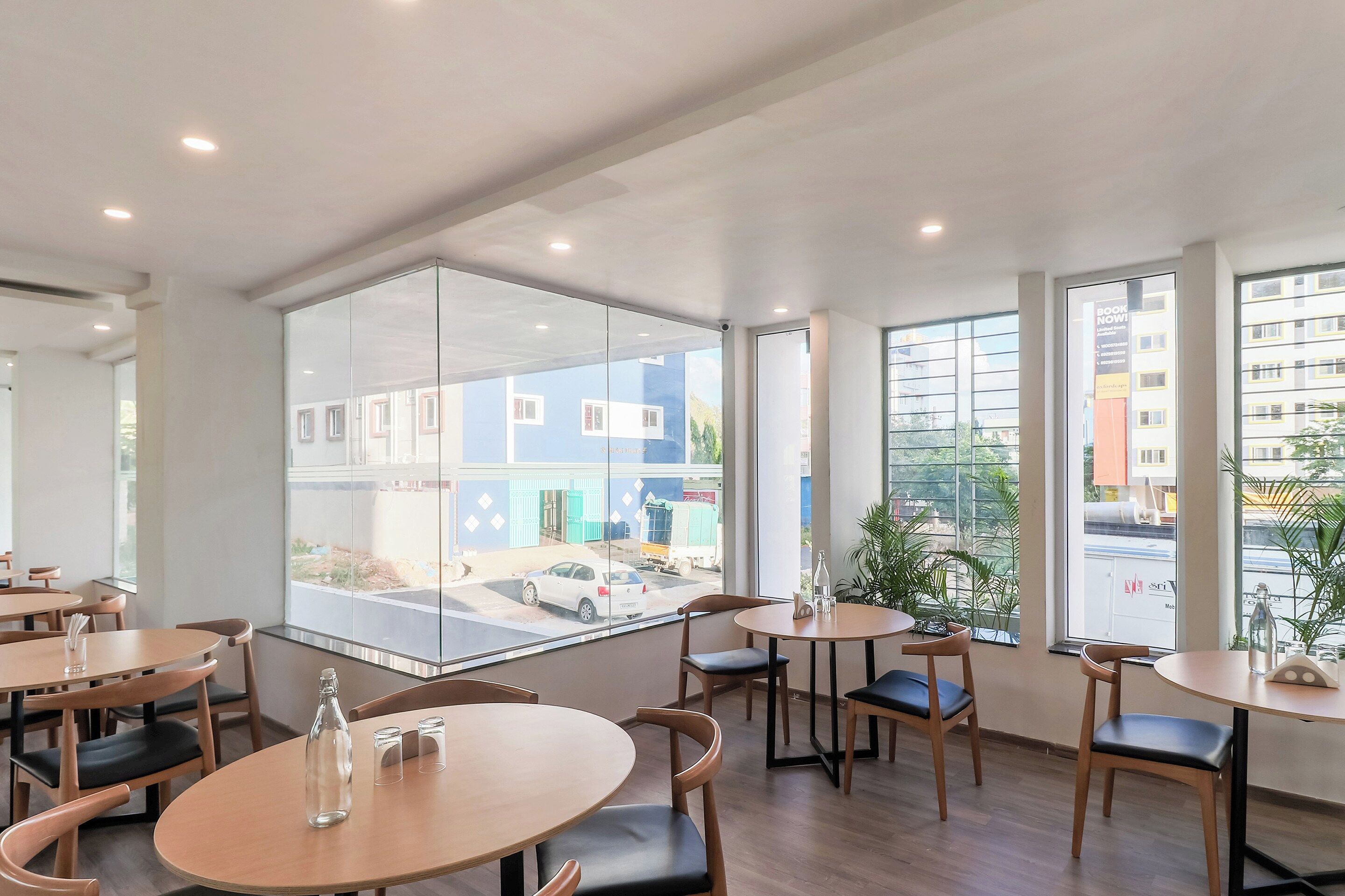 A modern interior with round tables and chairs, large windows with city views, and a glass partition.