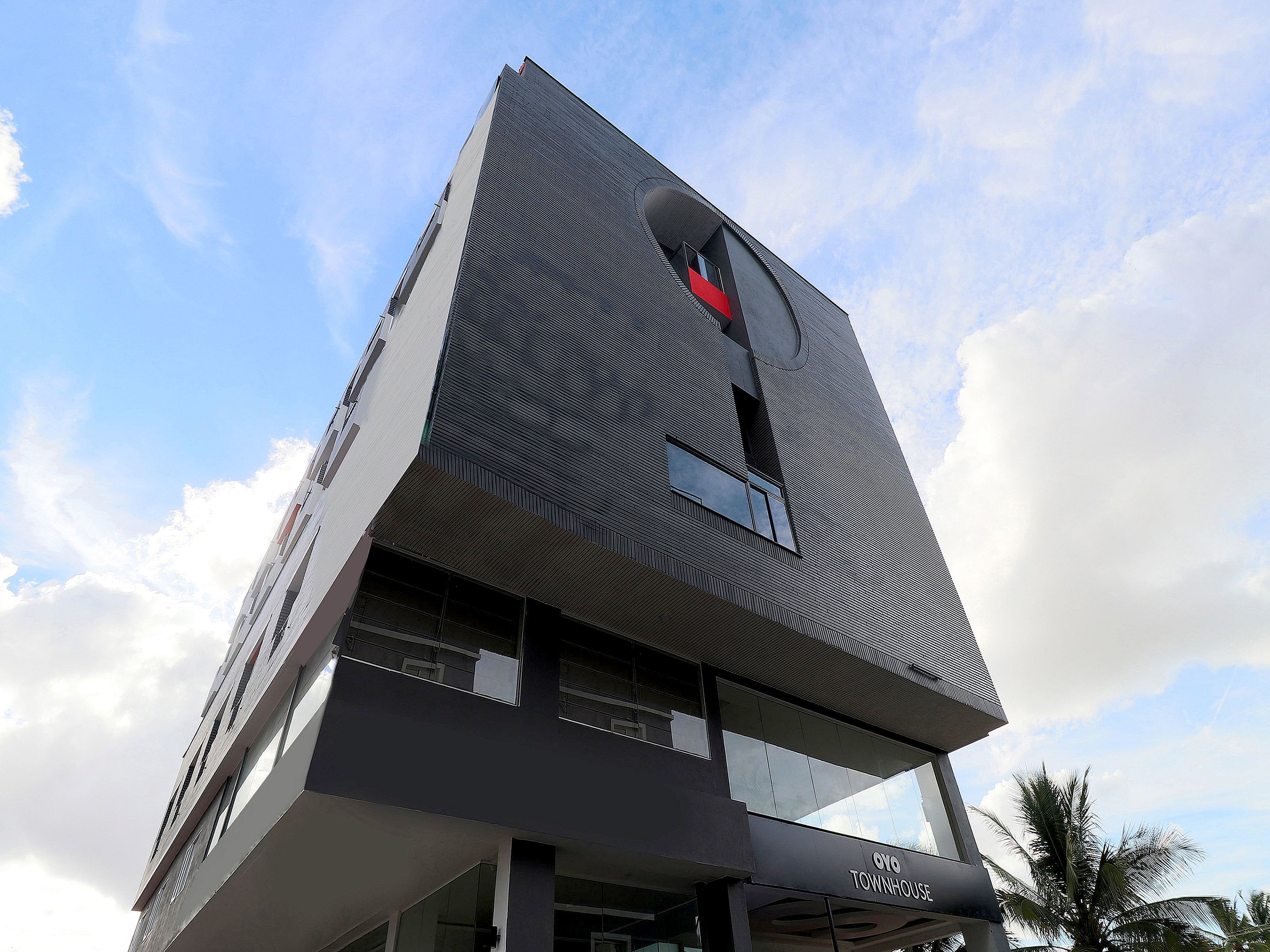 A modern building with a unique architectural design, featuring a prominent curved facade and a sign that reads 'OYO TOWNHOUSE'.