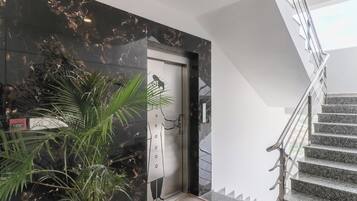 Un interno moderno con una parete in marmo, una scala e una porta dal design minimalista.