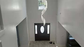 A staircase with a modern design, leading to a black door with a decorative glass panel.