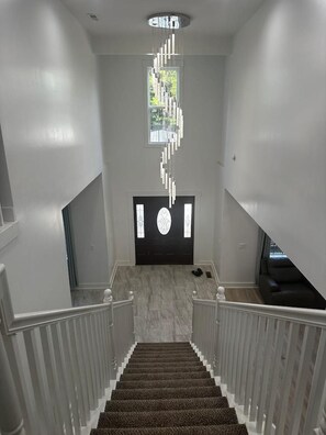 Eine modern gestaltete Treppe, die zu einer schwarzen Tür mit dekorativem Glasfeld führt.