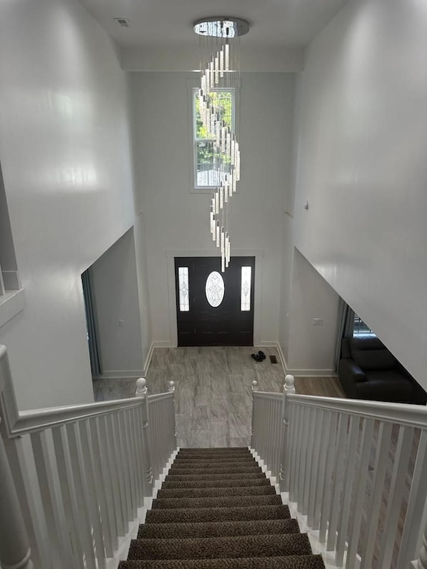 En trappa med modern design som leder upp till en svart dörr med en dekorativ glaspanel.