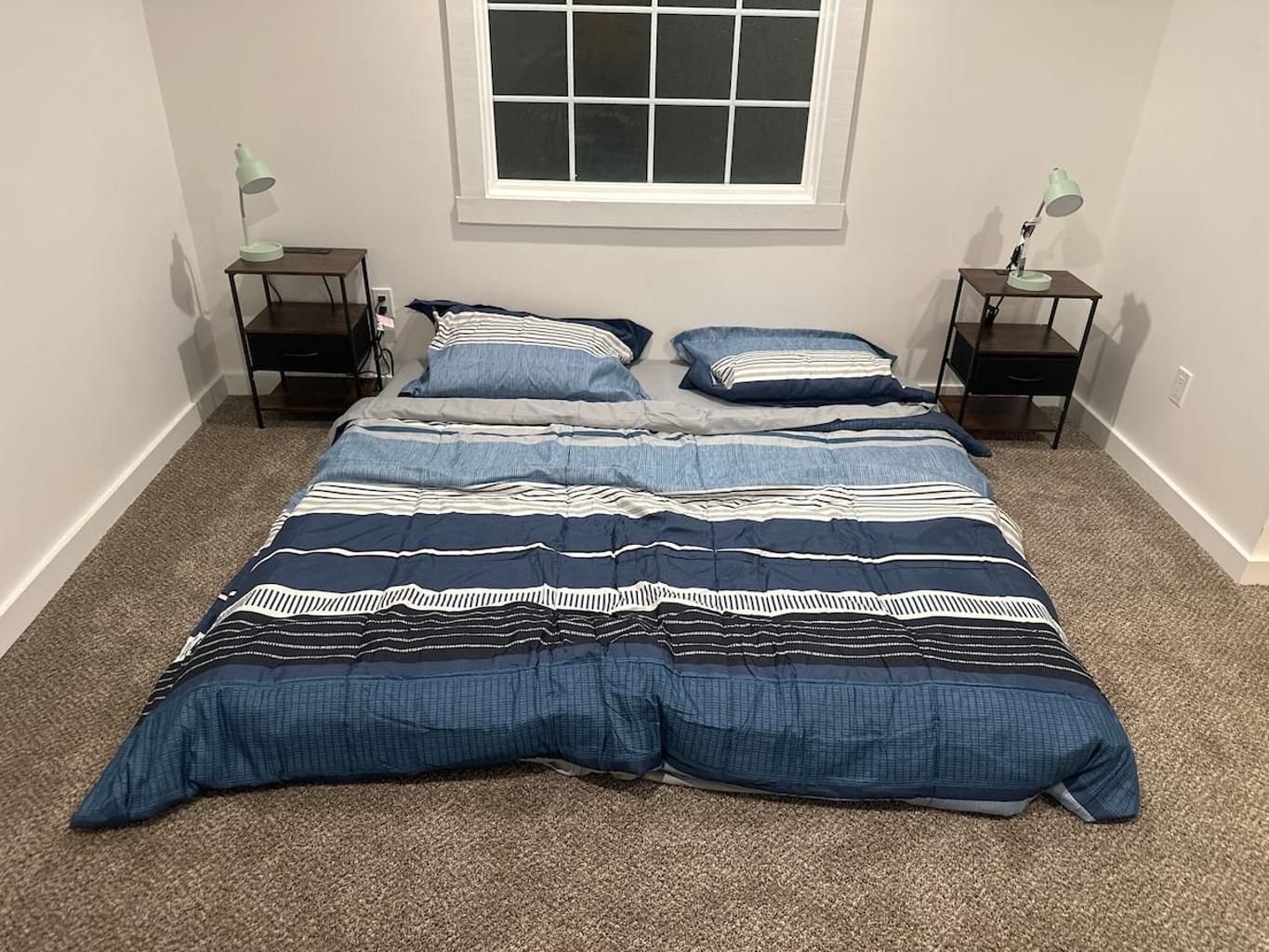 A bedroom with a large bed, two bedside tables, and a window.
