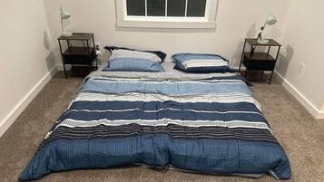 A bedroom with a large bed, two bedside tables, and a window.