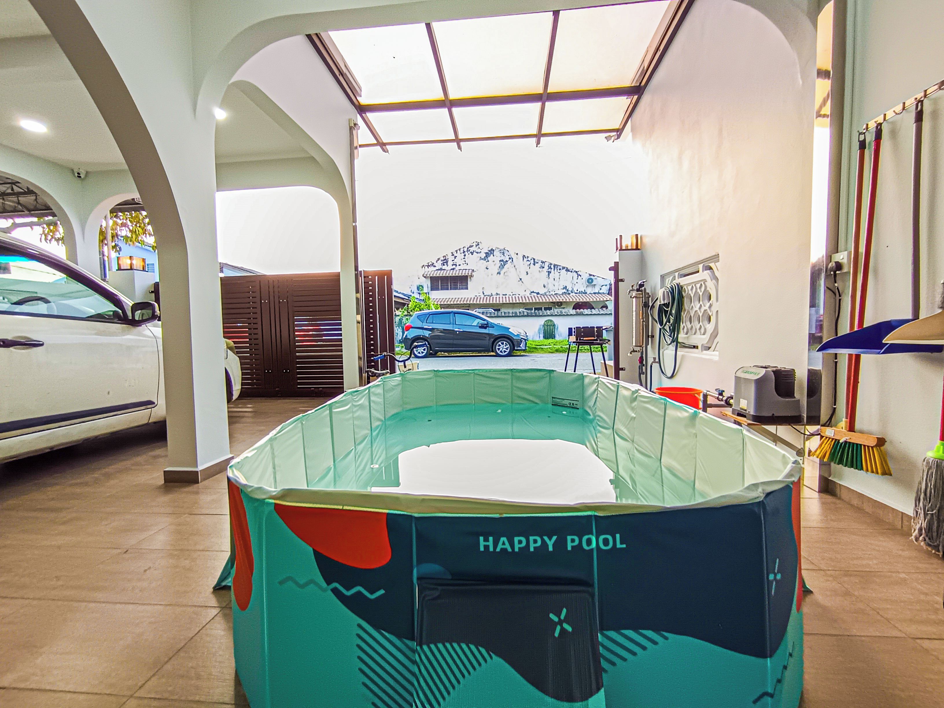 A pool area with a sign reading 'HAPPY POOL' and a view of parked cars outside.