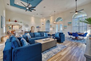 A spacious living area with a large blue sofa set, a wooden coffee table, and a dining table with blue chairs. - VRCC Villa Grand Lagoon (Cape Coral)