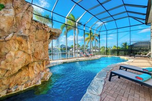 An indoor swimming pool with clear water, surrounded by a glass enclosure, and equipped with lounge chairs. - VRCC Villa Grand Lagoon (Cape Coral)