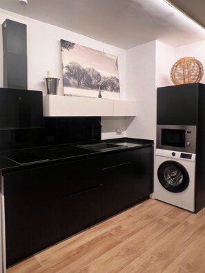 A modern kitchen with a black countertop, a built-in washing machine, and a microwave. - Live in Style in Madrid (Madrid)