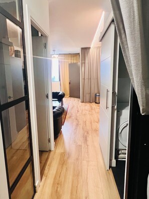 A hallway leading to a bedroom with a door, a small seating area with a chair, and a visible washing machine. - Live in Style in Madrid (Madrid)