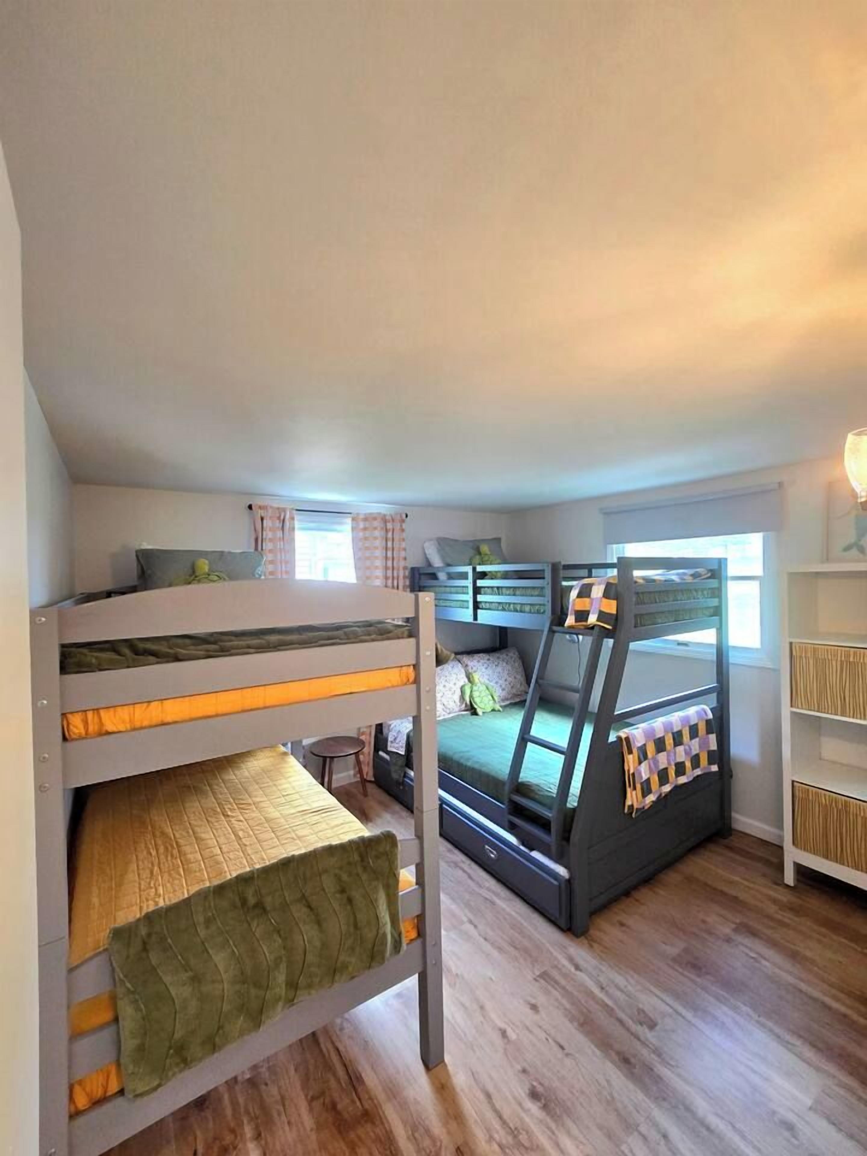 Une chambre avec des lits superposés, une fenêtre et une bibliothèque.
