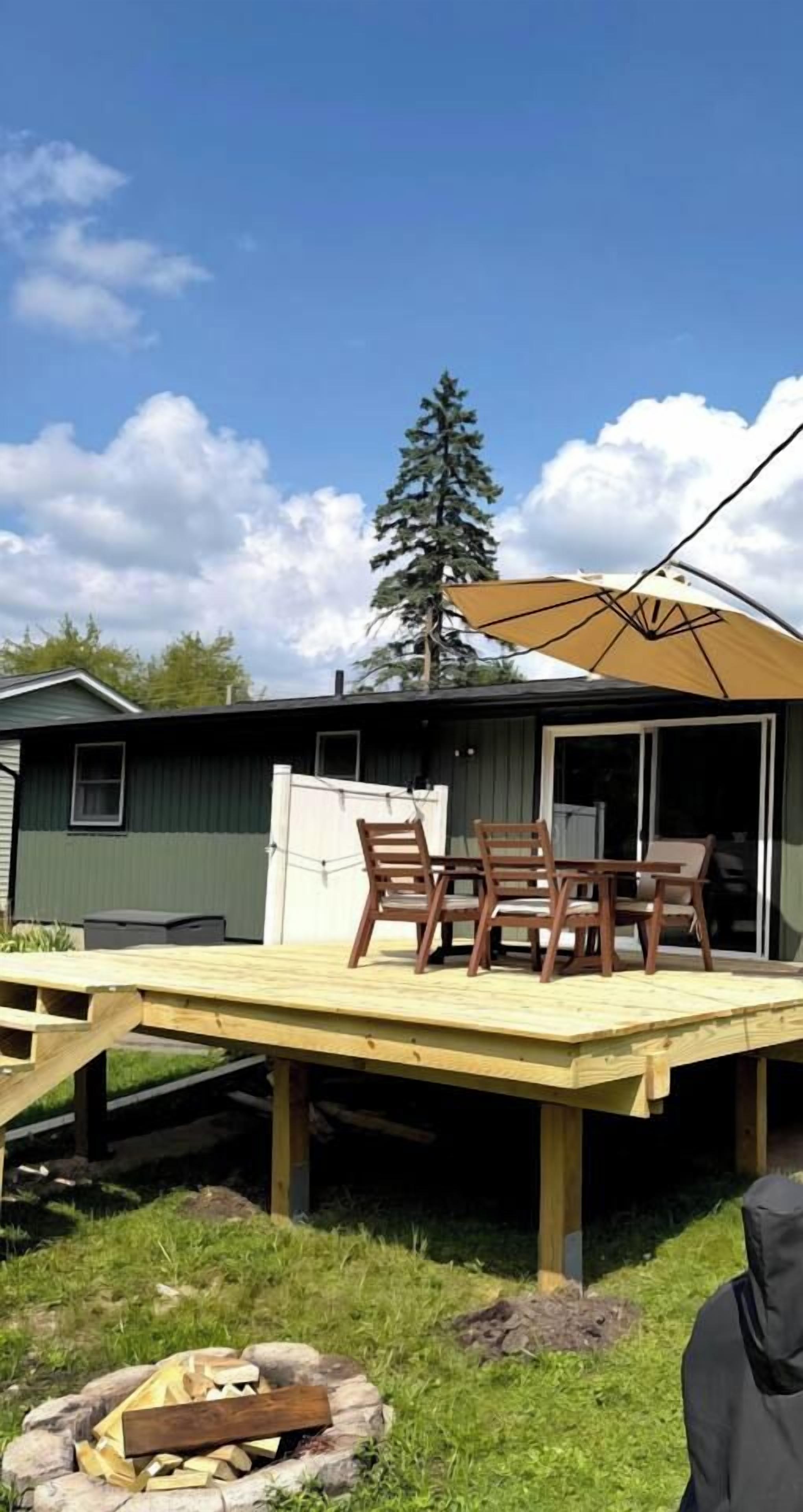 Une terrasse extérieure avec une table et des chaises, un foyer et un espace abrité avec un parasol.