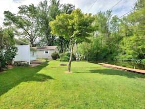 A residential property with a grassy yard, a small white building, and a wooden deck.