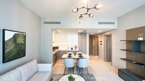 A modern living room with a sofa, dining table, and chairs, a kitchen in the background, and a ceiling light fixture. - Chic full Dubai Marina View 1 BR apartment in LIV Marina (Dubai)