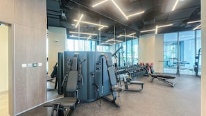 Ein Fitnessstudio mit Trainingsgeräten, großen Fenstern und modernem Design.