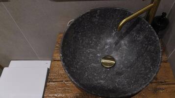 A bathroom with a black marble sink, gold faucet, and a white toilet.