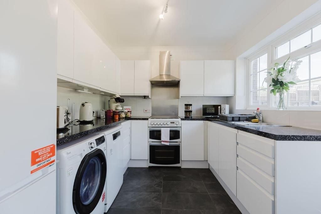 A modern kitchen with a built-in washer, oven, microwave, and stainless steel range hood.