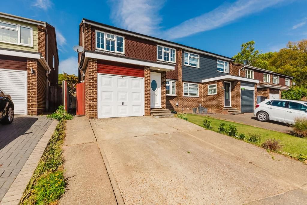 A residential street with houses, a driveway, and a parked car.