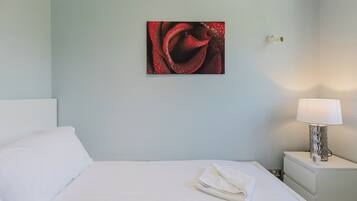 Une chambre d’hôtel avec un lit, une table de chevet avec une lampe et une œuvre d’art accrochée au mur.