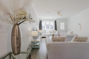 A modern living room with a white sofa, a glass coffee table, and a vase with flowers.
