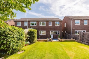 A two-story brick house with a well-maintained lawn and a wooden fence. - Luxury 4BR Oasis - 1Gbps WiFi & Parking (Cheshunt)