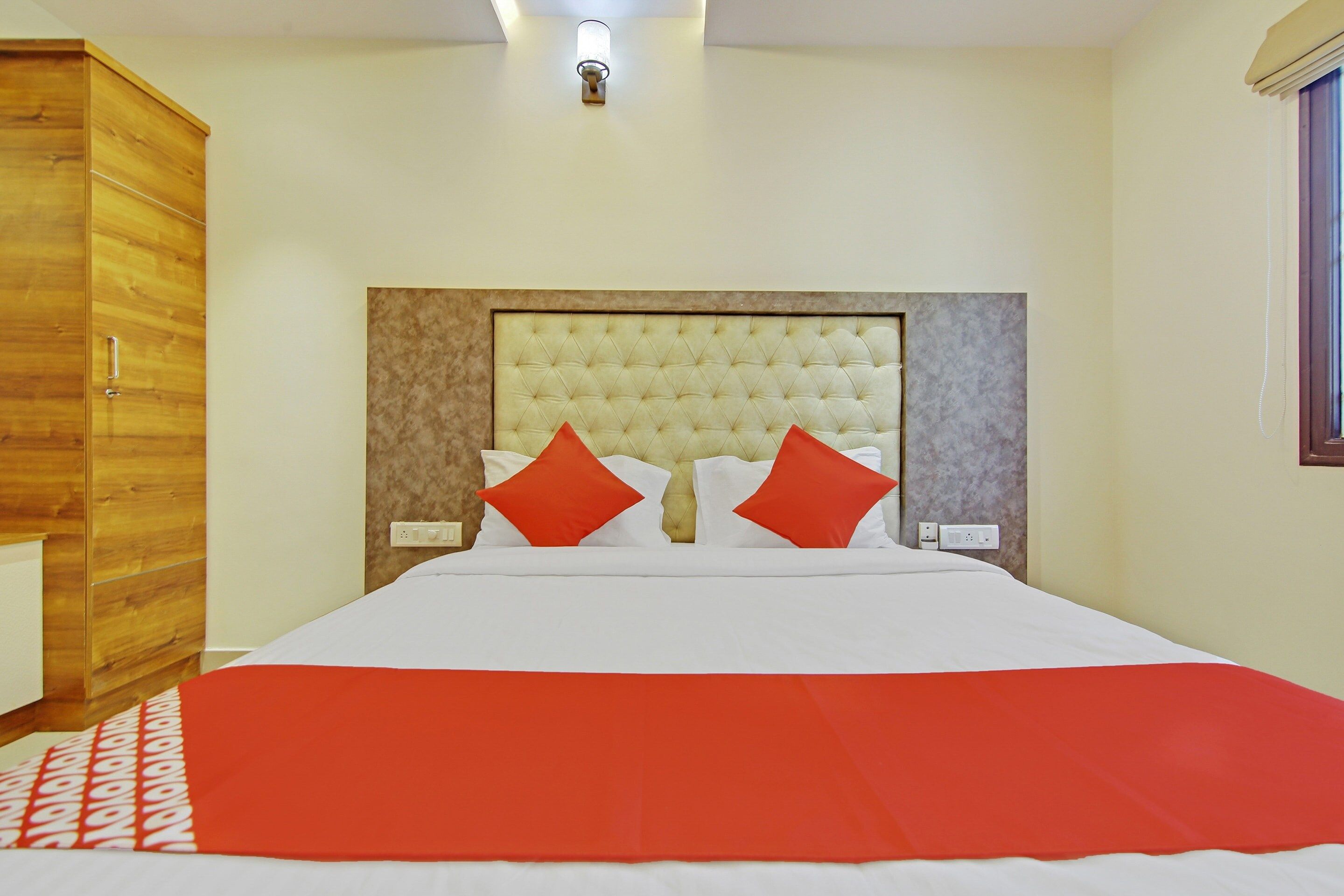 Una habitación de hotel con una cama grande, un armario de madera y una lámpara en el techo.