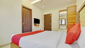 A hotel room with a bed, a television, a mirror, and a ceiling fan.