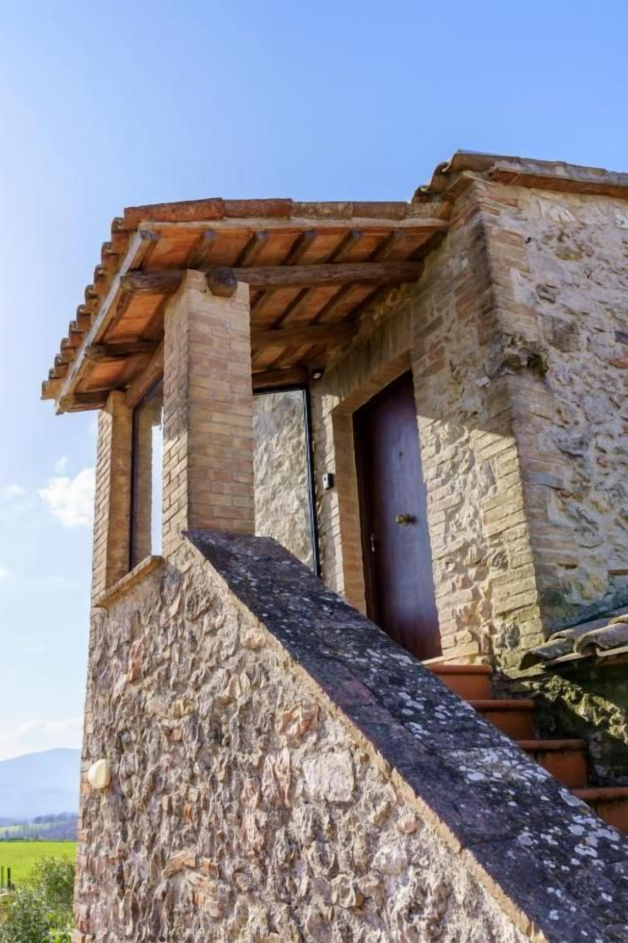 Un edificio de piedra con un balcón de madera y una puerta.