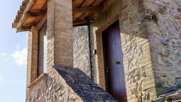 Un edificio de piedra con un balcón de madera y una puerta.