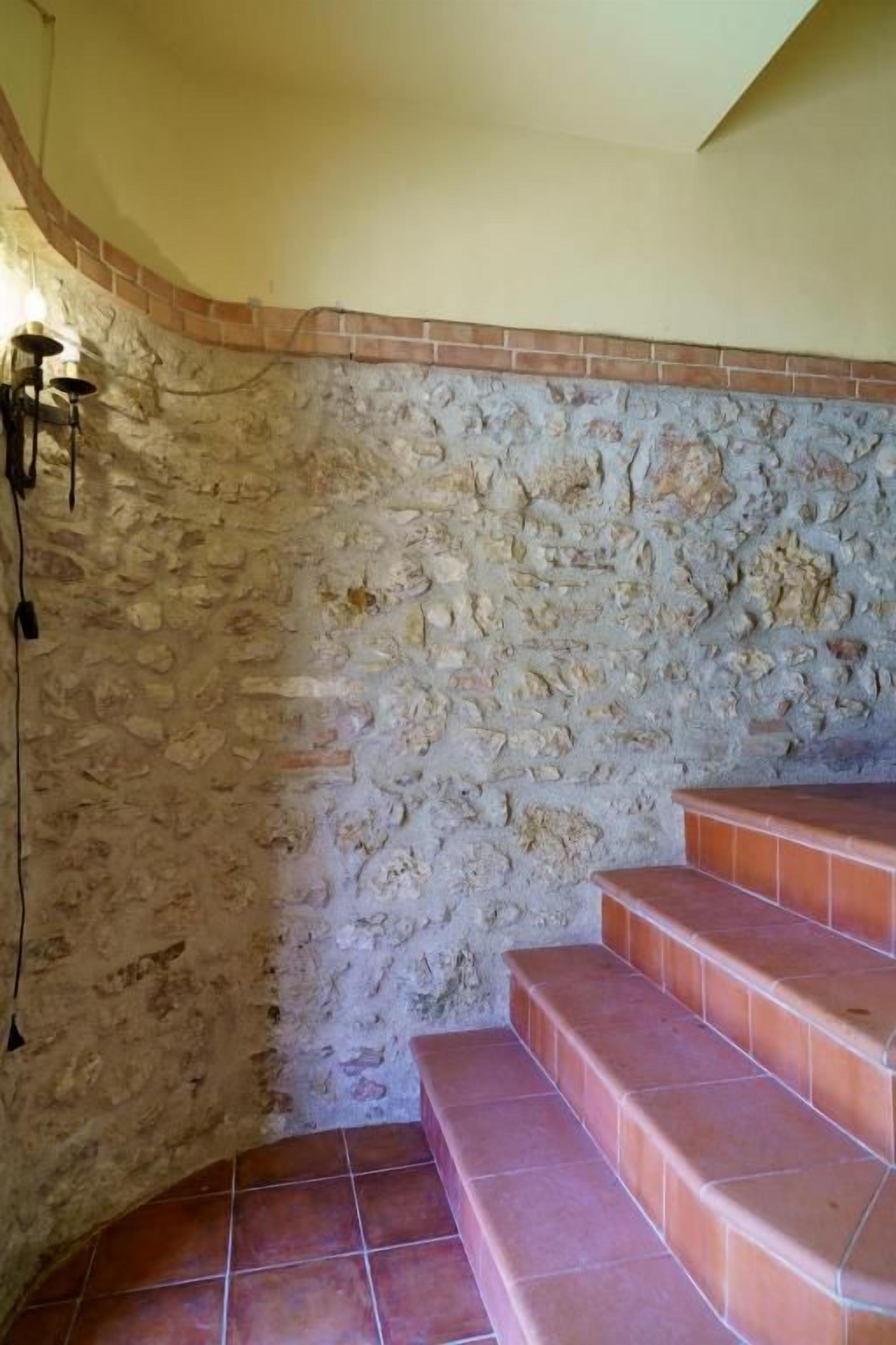 Una escalera con un muro de piedra y peldaños de cerámica.