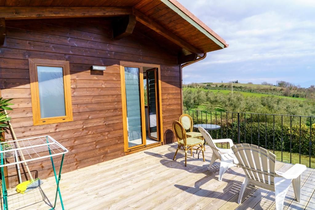 A wooden cabin with a deck, two chairs, a table, and a metal drying rack.