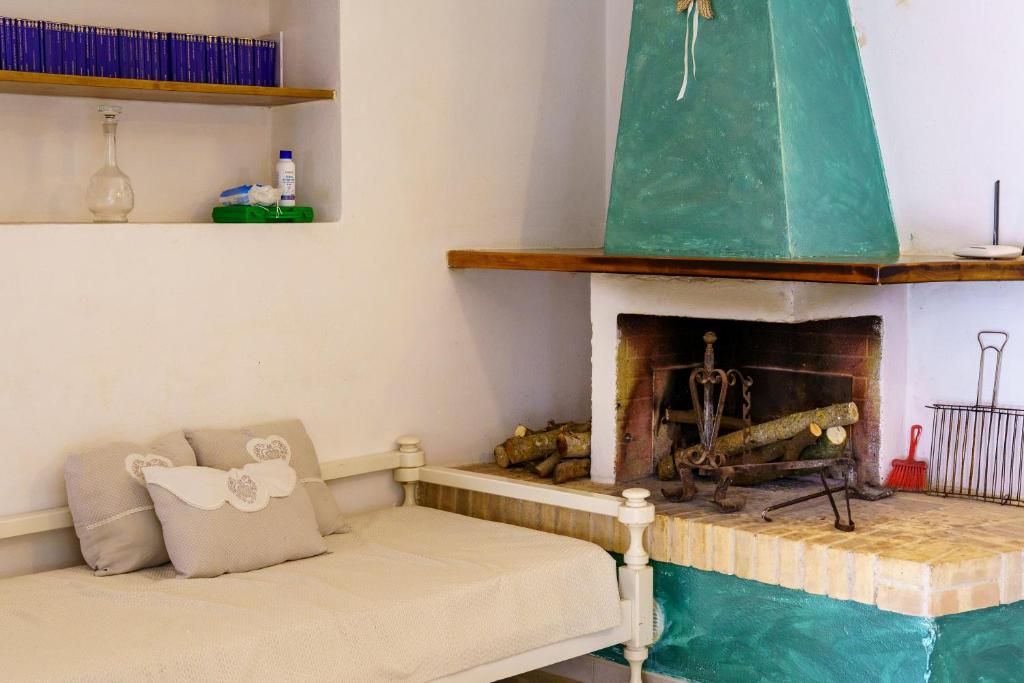 A room with a bed, a fireplace, and a shelf with books and bottles.