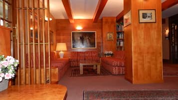 Una habitación acogedora con piso de madera, un sofá, una mesa y una estantería.