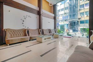 A lobby with a seating area, a reception desk, and a view of the outside.