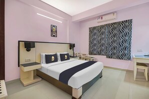 Una habitación de hotel con cama, mesitas de noche, escritorio y aire acondicionado.