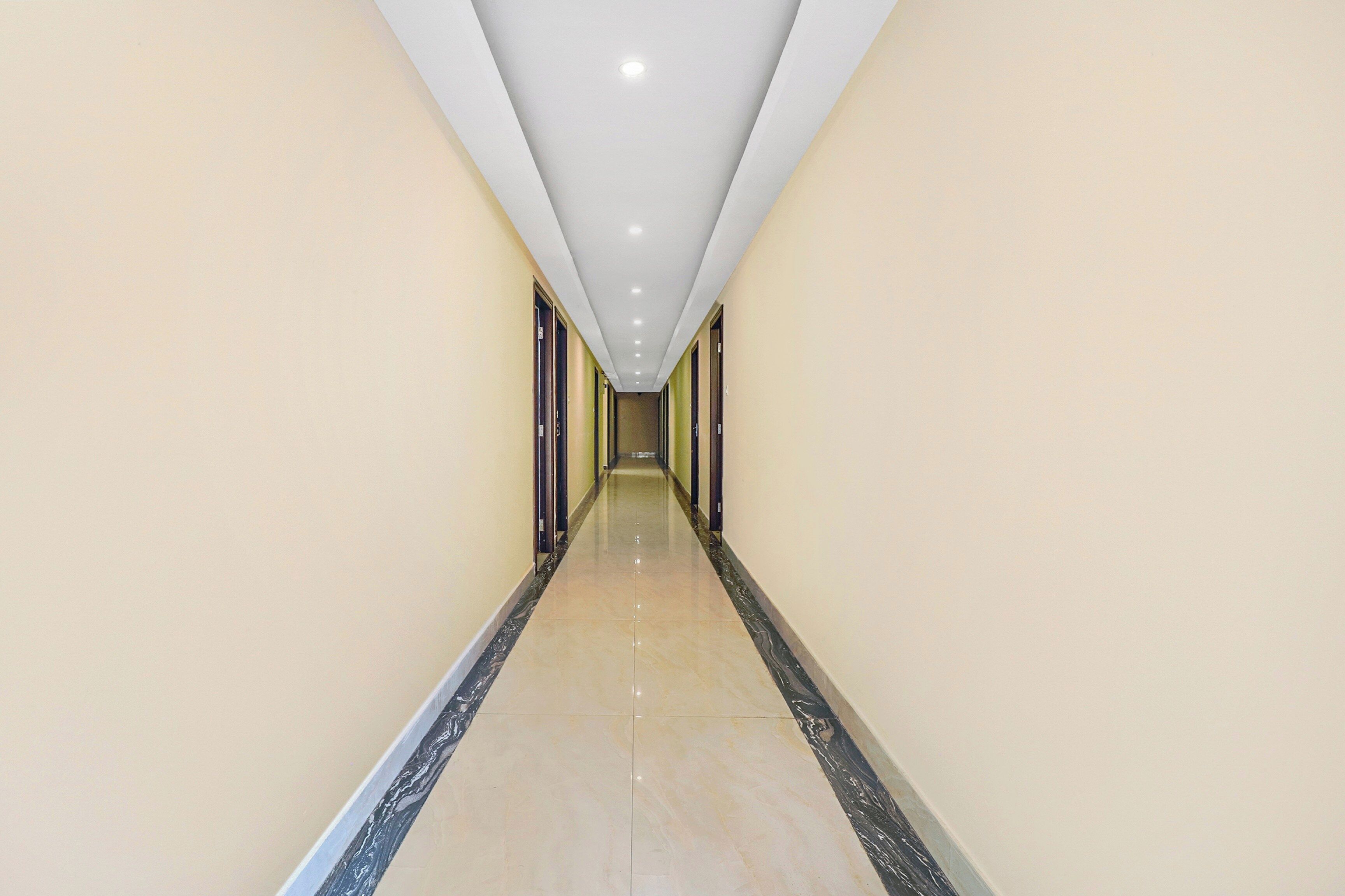 A long, narrow hallway with a polished floor and recessed lighting on the ceiling.
