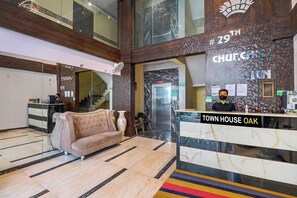 Un hall con mostrador de recepción identificado como 'Town House Oak', un sofá, suelo de mármol y una pared con un cartel que dice '#29 Church's Inn'.