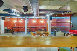 A spacious indoor area with multiple tables and chairs, a brick wall, and exposed ductwork on the ceiling. - Collection O 29 Church's Inn Near Cubbon (Bangalore)