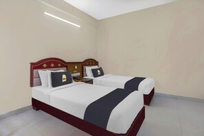 Una cama doble con cabecera de madera, dos almohadas, una mesita de noche y una mesita auxiliar.