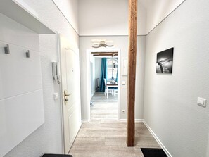 A hallway with a wooden column, a white door, and a framed picture on the wall. - House With sea View - Apt. 4 (Wyk auf Foehr)
