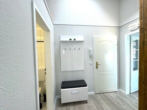 A hallway with a white bench, a wall-mounted cabinet, and a door. - House With sea View - Apt. 4 (Wyk auf Foehr)