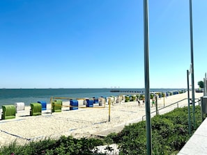 A beach with rows of colorful beach chairs and umbrellas, a clear sky, and a distant pier. - House With sea View - Apt. 4 (Wyk auf Foehr)