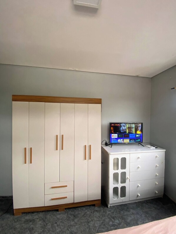 A bedroom with a wardrobe, a TV, and a dresser.