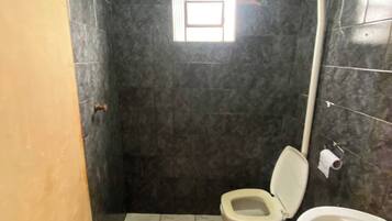Un bany petit amb vàter, un lavabo i una finestra.