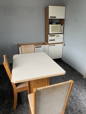 Una pequeña zona de comedor con una mesa blanca y sillas de madera.