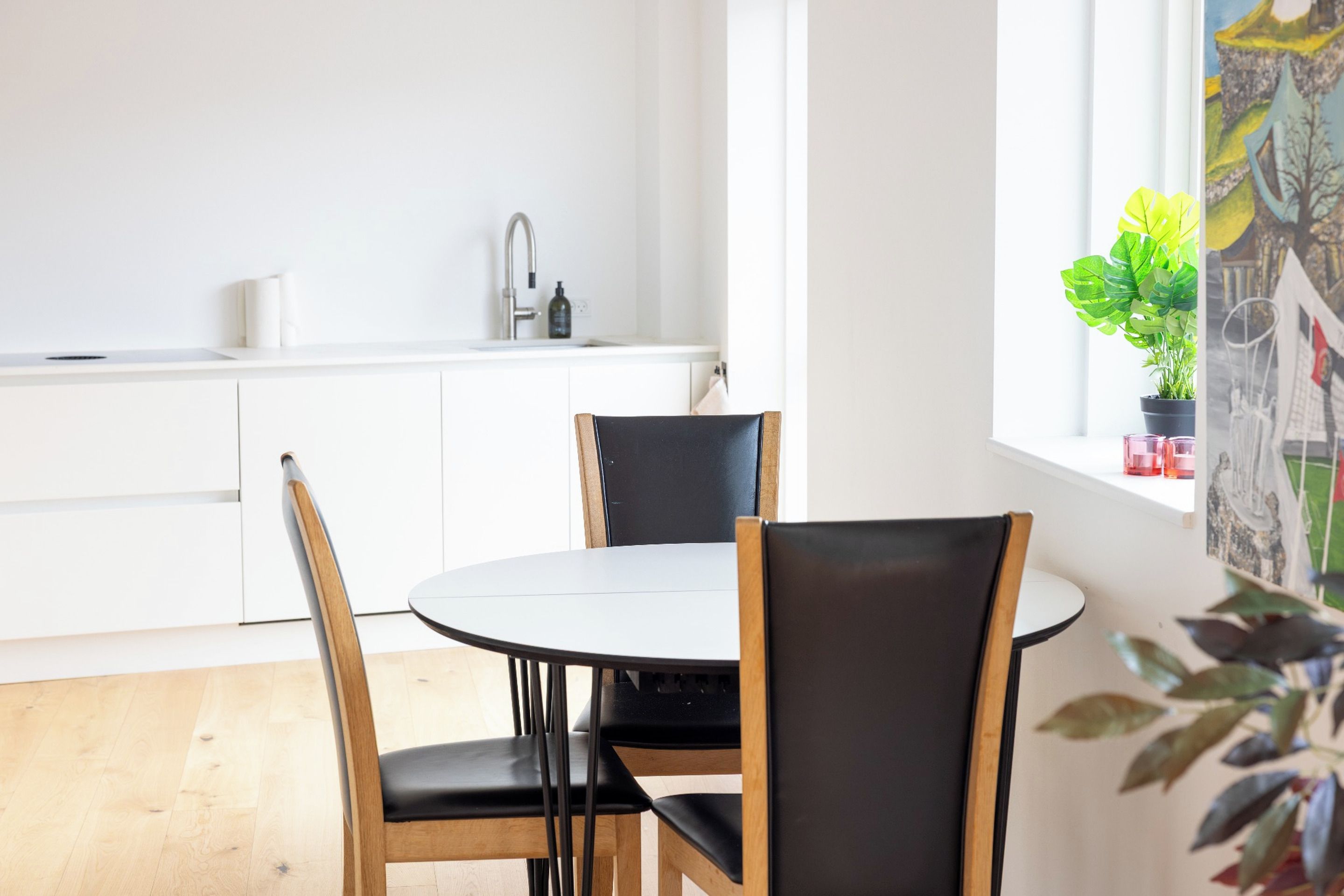 A modern kitchen with white cabinets, a round dining table, and two chairs.